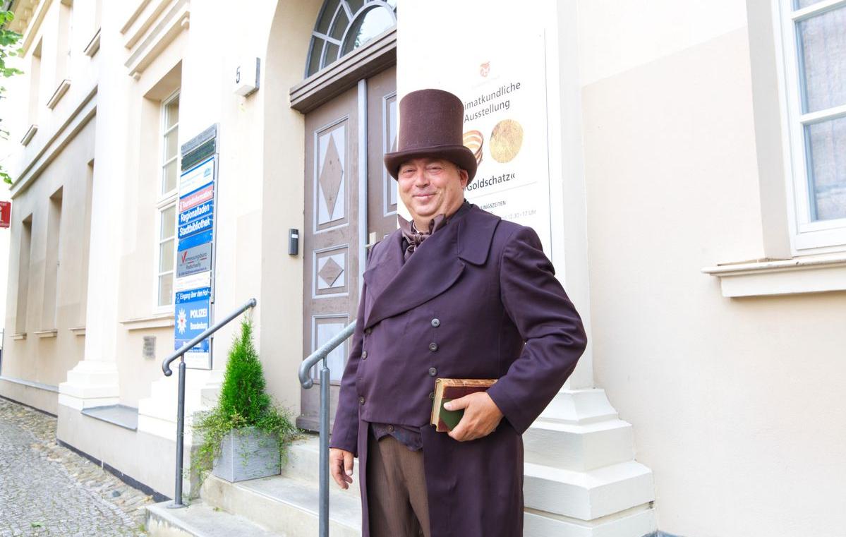 Auf dem Bild ist Stadtführer Carsten Dräger in seinem Stadschreiberkostüm vor der Tourist-Information der Wasserstadt abgebildet.